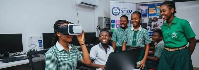 A secondary school pupil exploring with a virtual reality headset while classmates watch in a computer room